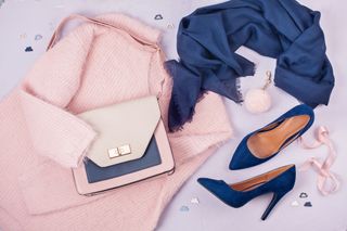 Flat lay of woman clothing and accessories in pastel colours.