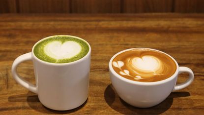 matcha vs coffee - a matcha latte next to a latte on a wooden table