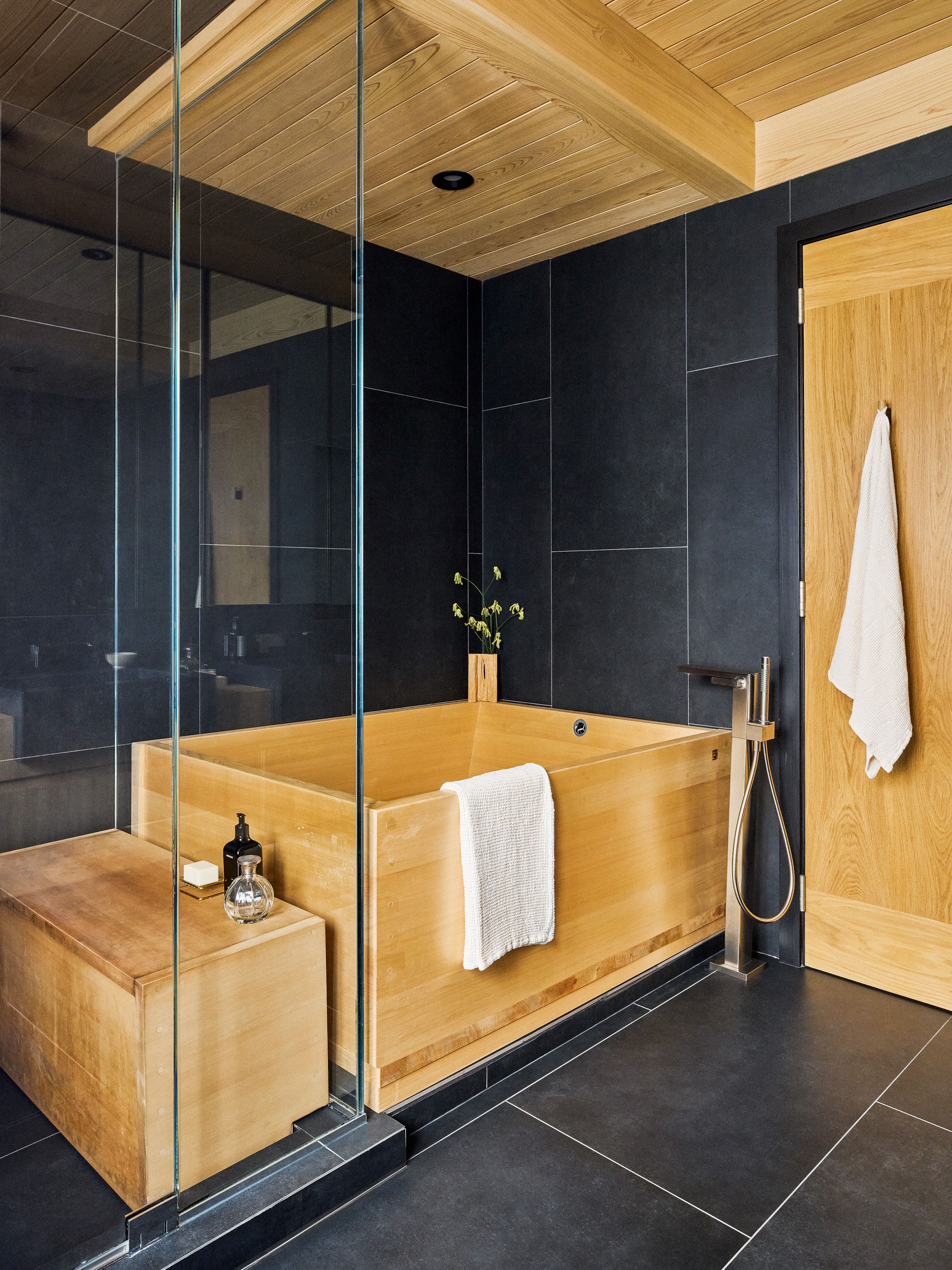 Bathroom with black tiles and wood Japanese-style soaking tub