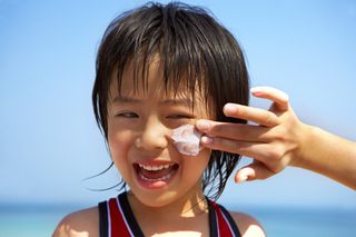 a close up of a kid's face with a smear of sun cream on