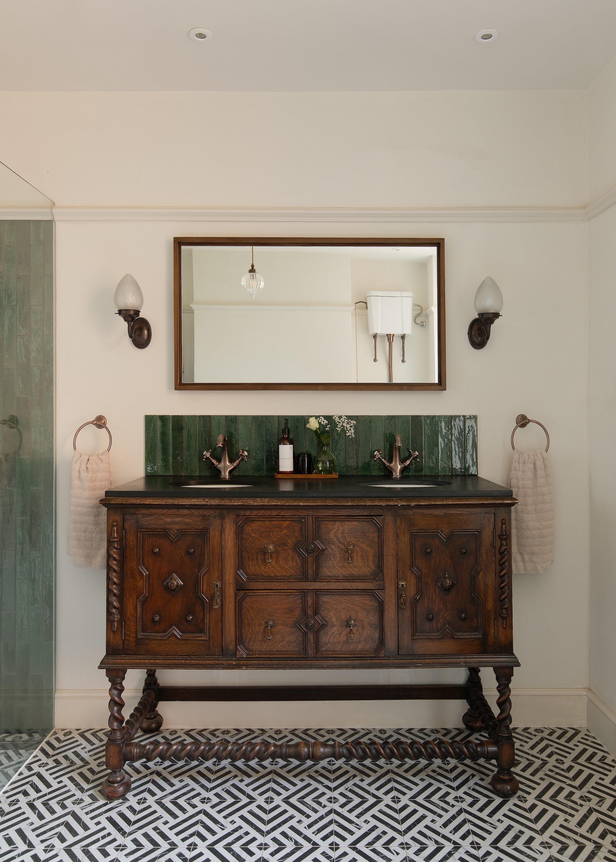 a vintage sideboard repurposed as a vanity basin with a green splashback and brass taps
