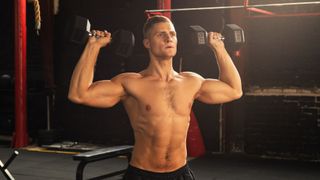 a photo of a man doing the dumbbell push press