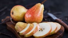 Whole and sliced fresh pears on a wooden board