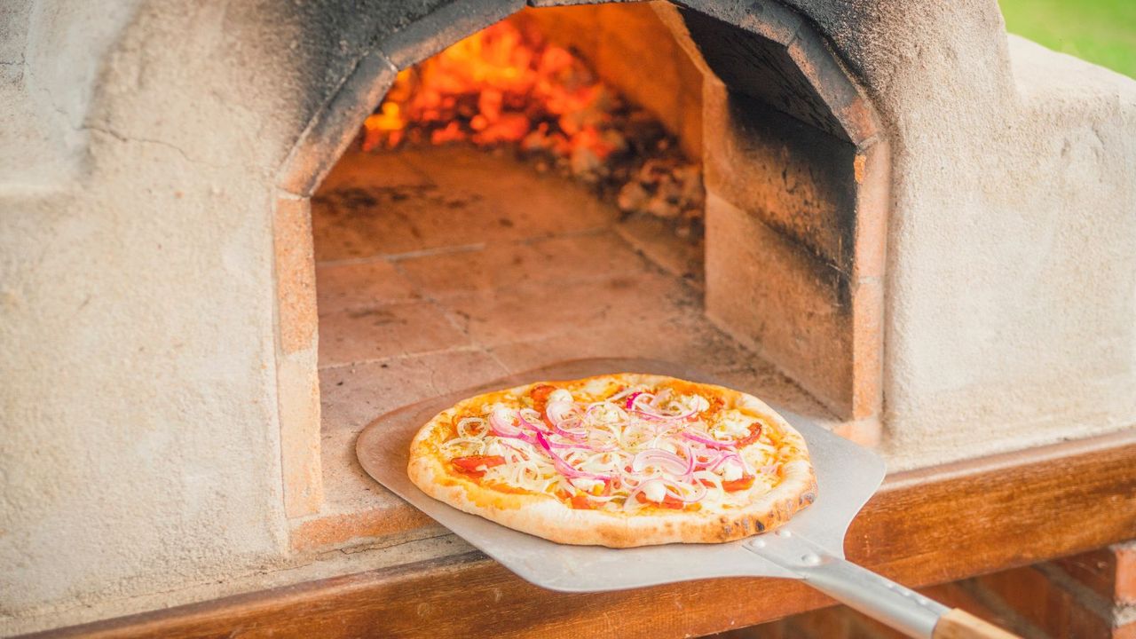 Removing a pizza from a hot pizza oven