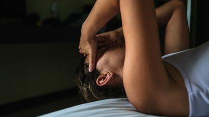 Woman lying on her back in bed with hands over head to represent discount from what causes a UTI 