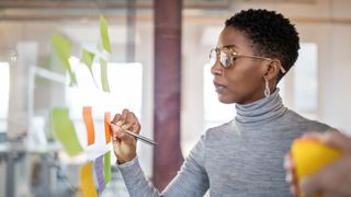 Woman doing small two minute task on colourful post-it notes