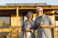 Senior couple drinking coffee and enjoying in front of the cabin house