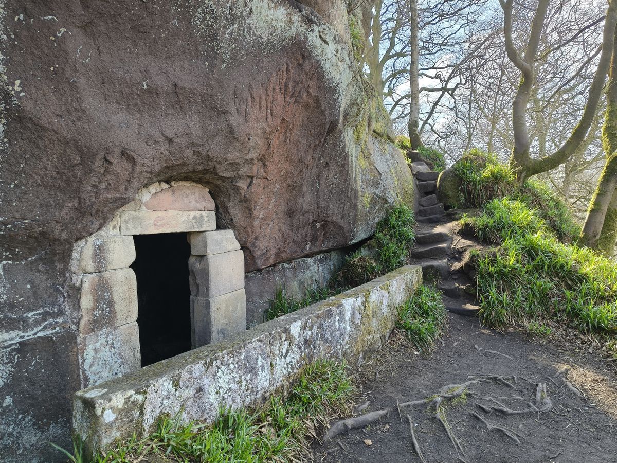 Large boulder next to a path and trees
