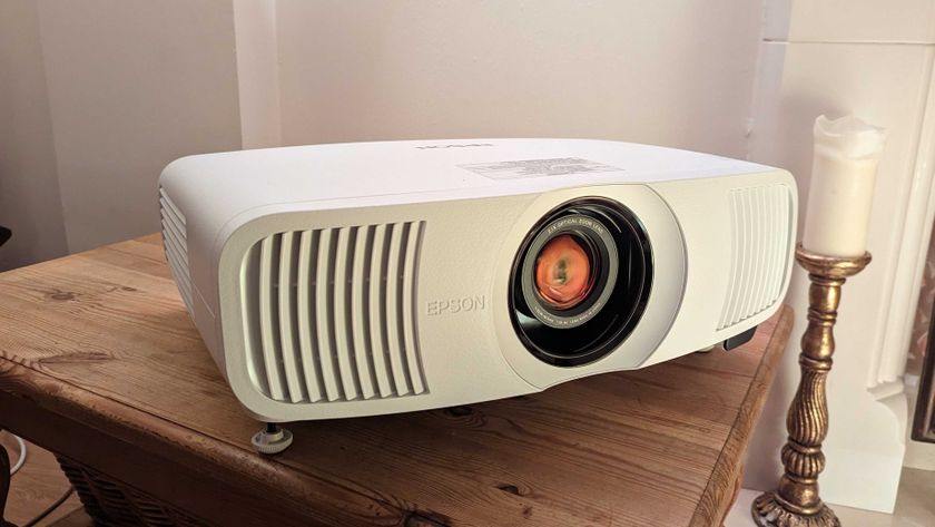 The Epson EH-LS11000W projector on a wooden table in front of a white wall