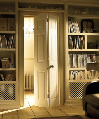 Cream coloured bifolding door leading from hallway into a living room with shelves