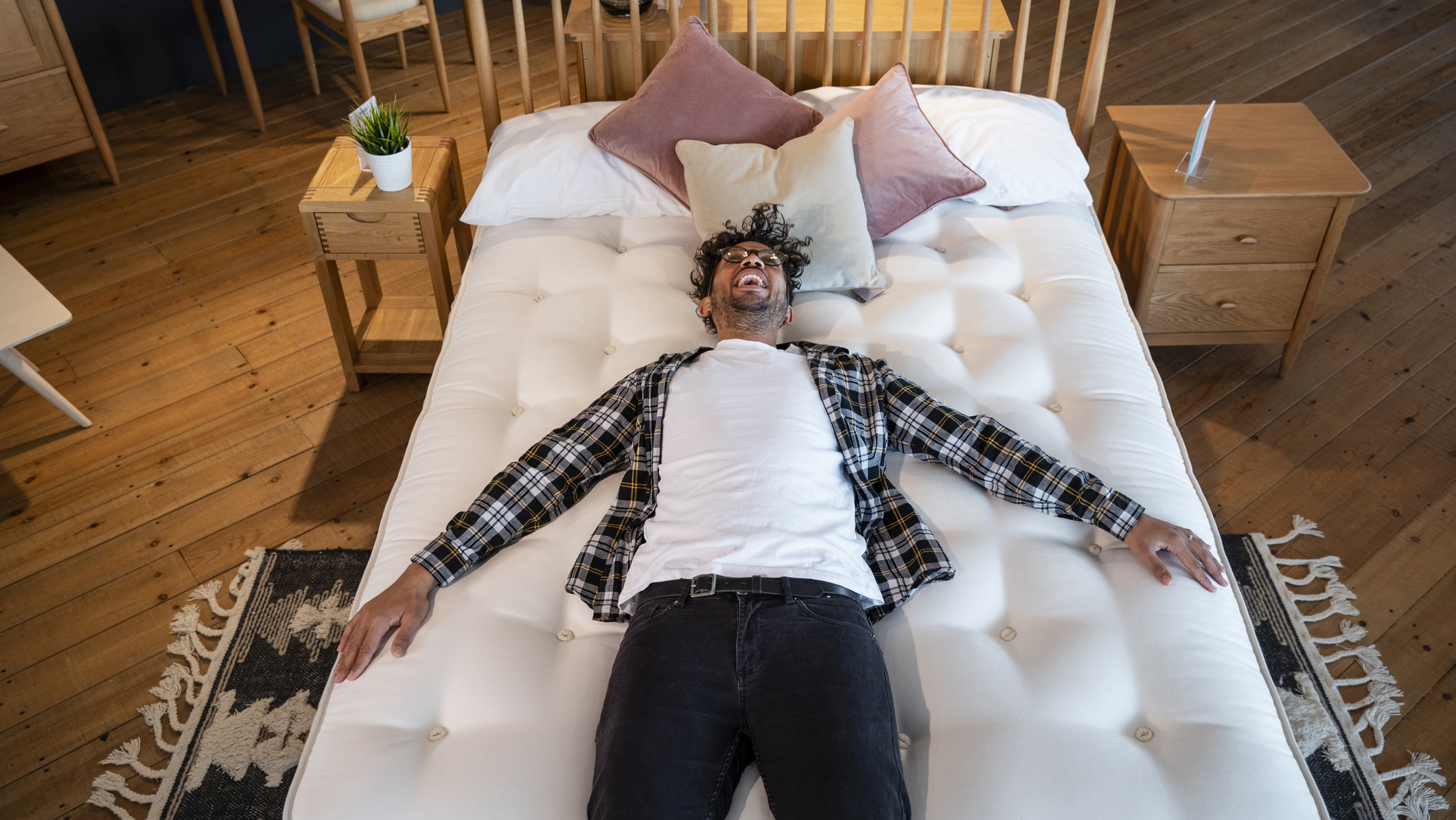 A man lies on top of a comfortable white mattress placed on a support spring.