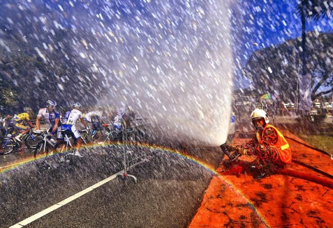 A fireman helps the riders cool down at the Tour de Langkawi and inadvertently creates a rainbow