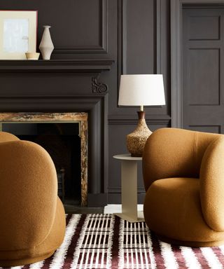 dark and sophisticated living room with black walls and warm brown sculptural armchairs