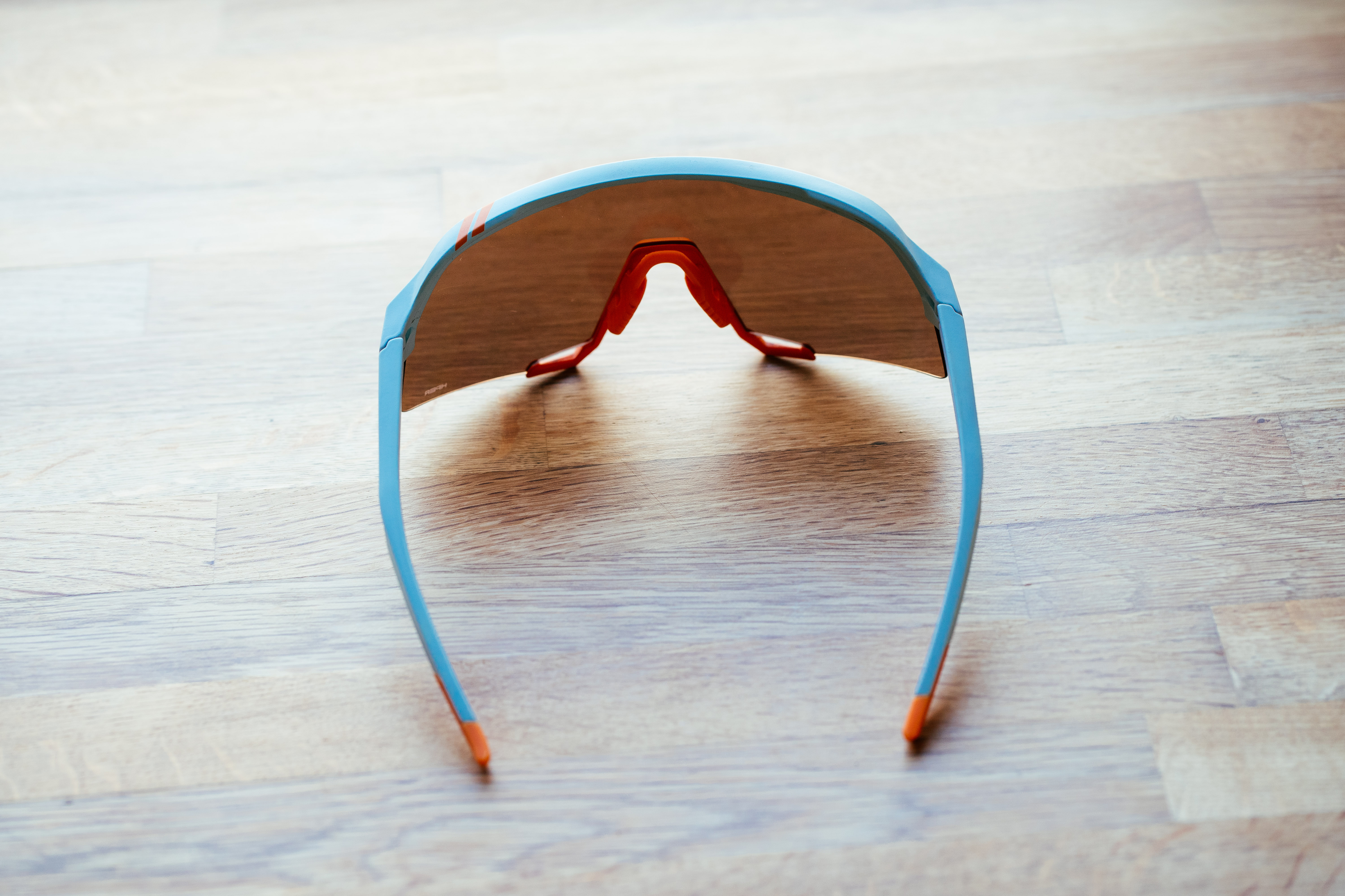 A blue framed set of sports glasses on a wooden surface