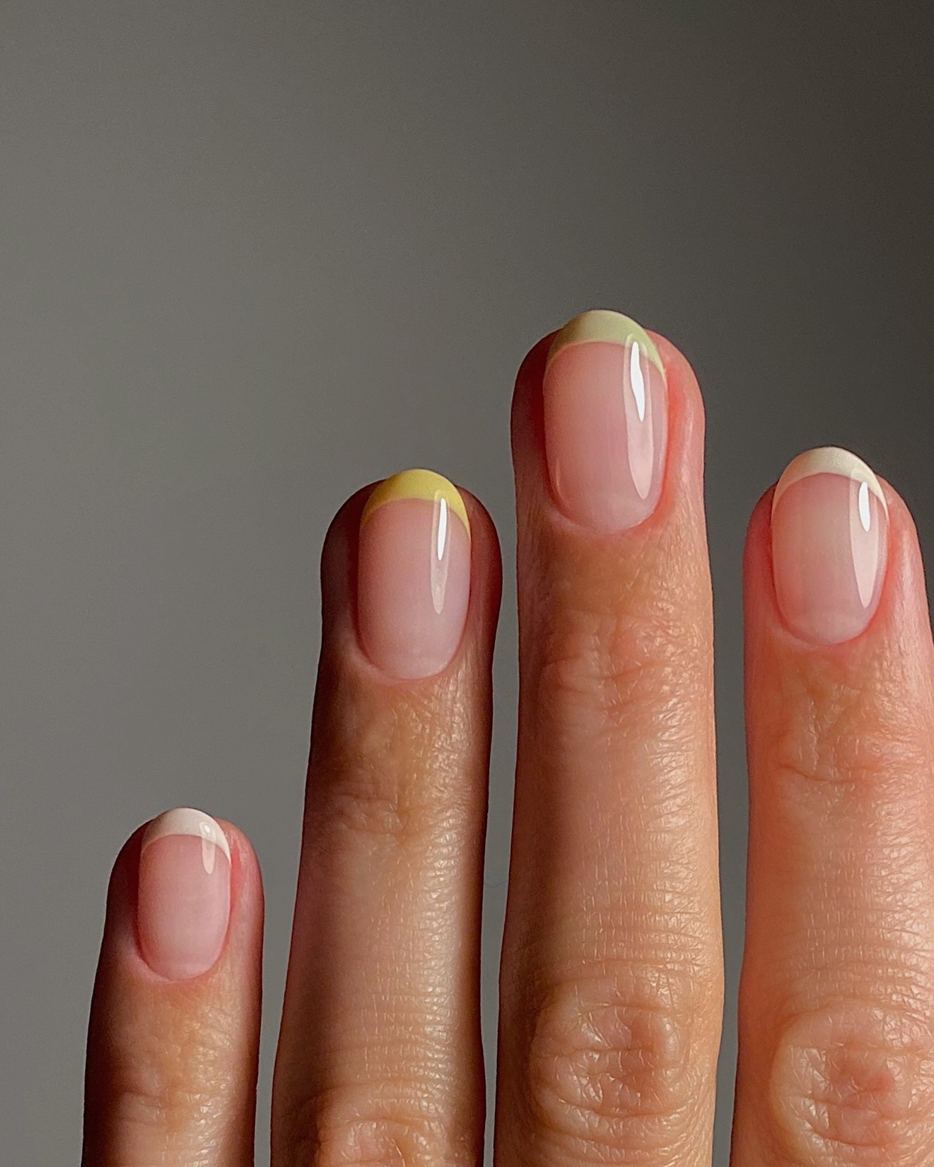 A close-up of longer oval nails with a different pastel French manicure on each nail