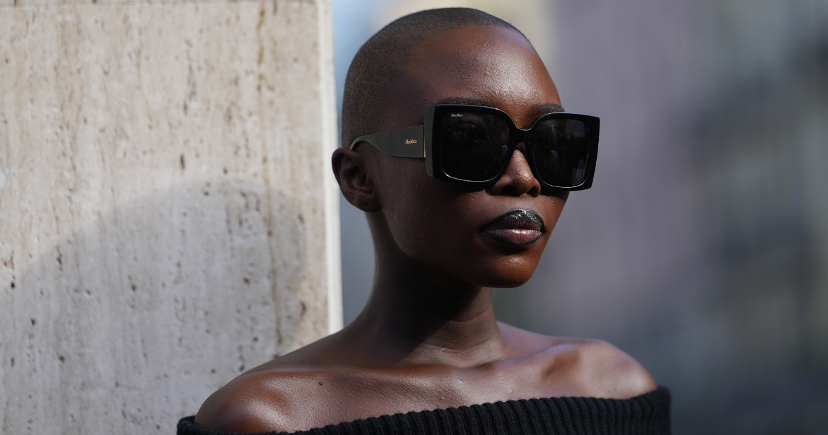 Concealers for dark skin Amina Seck wears a shaved close-cropped black hairstyle, oversized square black sunglasses with thick temples and dark lenses, a black ribbed knit off-the-shoulder sweater showing bare shoulders, outside Max Mara, during Milan Fashion Week - Womenswear Spring/Summer 2026, on September 25, 2025 in Milan, Italy