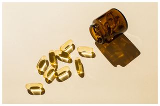 Omega 3 fish oil capsules and a glass bottle on a beige background