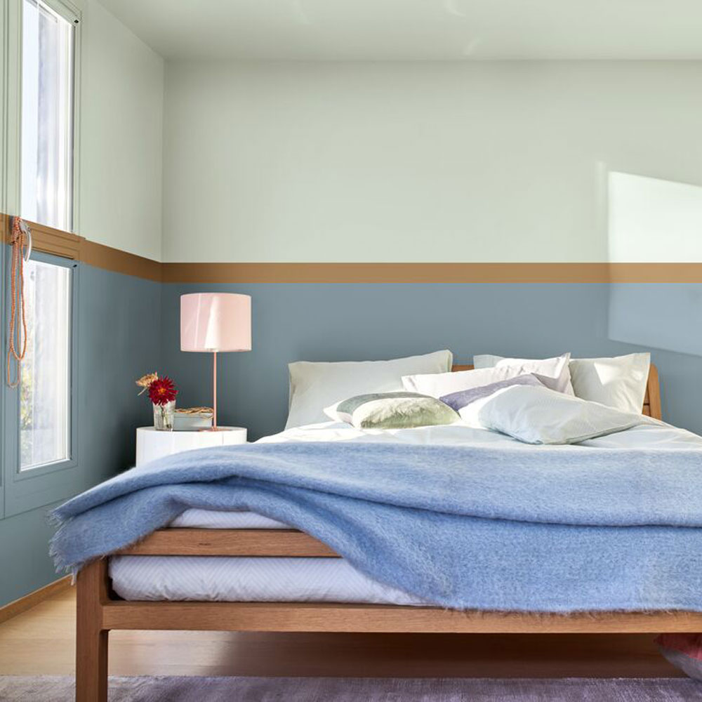 Small bedroom with wooden double bed, round side table and blue walls