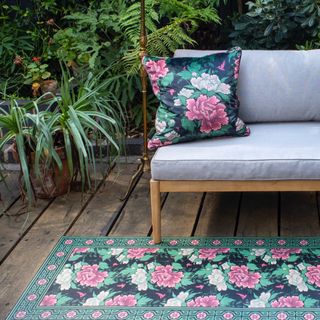 garden with bench on decking, patterned rug and matching cushion on bench