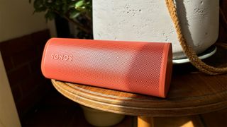 Sonos Roam 2 wireless speaker on wooden table next to plant pot