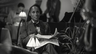 Brandy smiles while holding a newspaper in Black Mirror