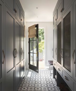 mud room with dark cabinets and door open with patterned tiled loors