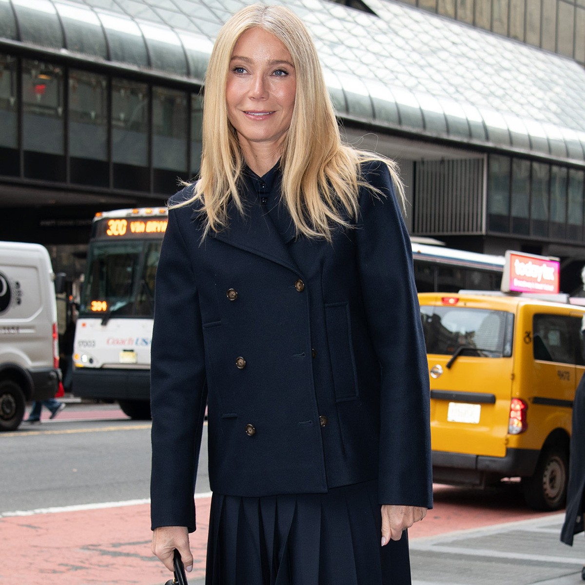 Gwyneth wears a navy blazer and navy pleated skirt.