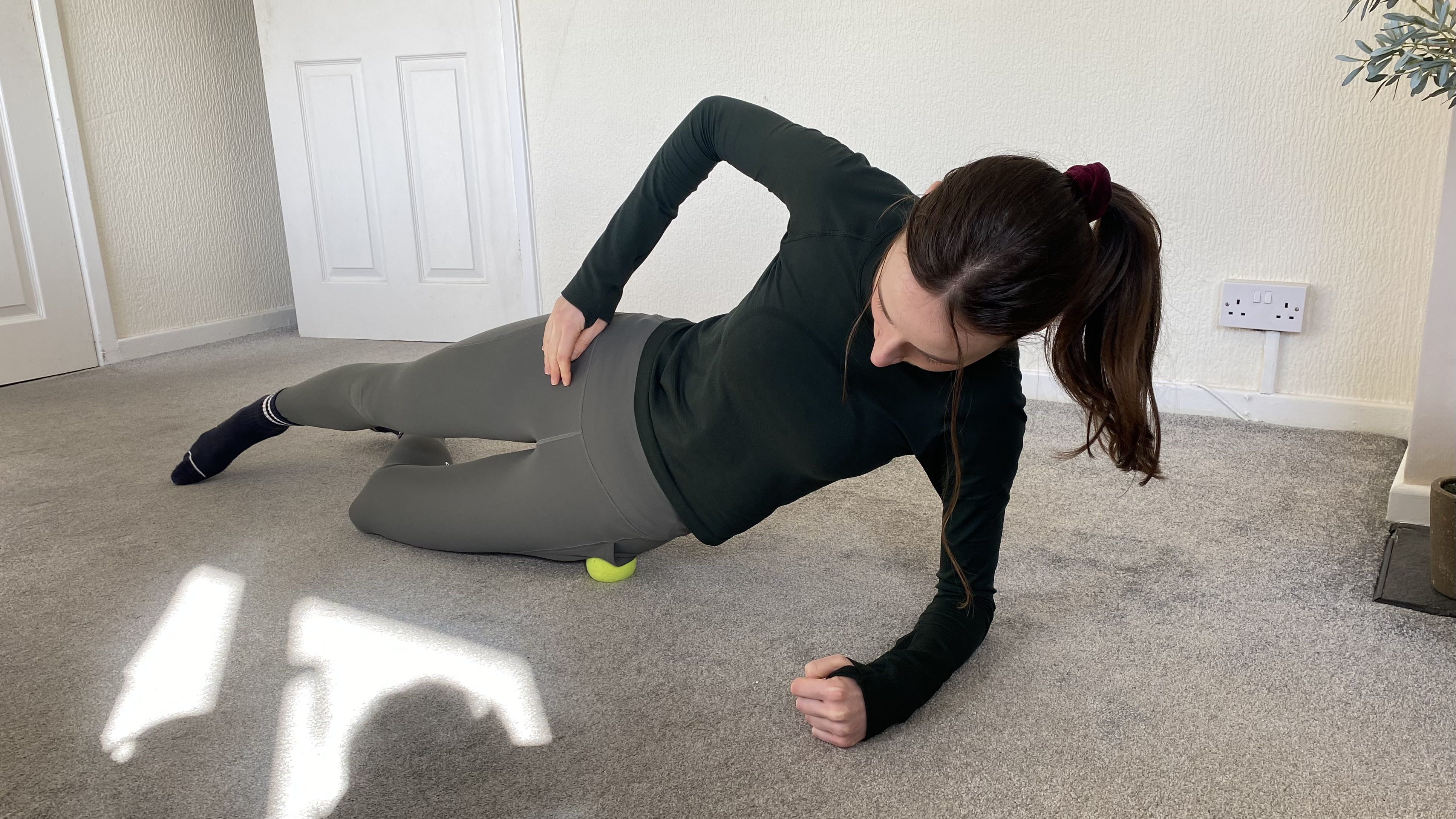 Woman lying on her side, a small yellow ball underneath her hip