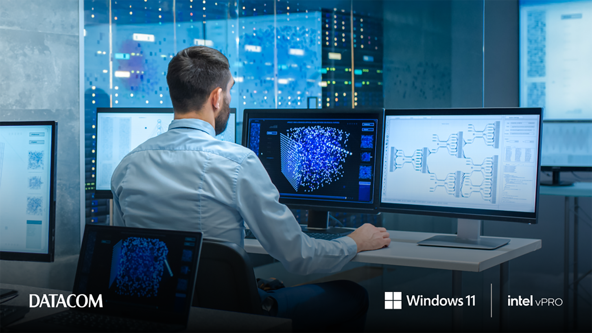 A man with his back to the camera working across three screens, all of which show different types of data modelling