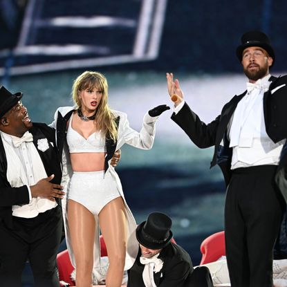 Taylor Swift and Travis Kelce on stage in black and white outfits during the Eras Tour