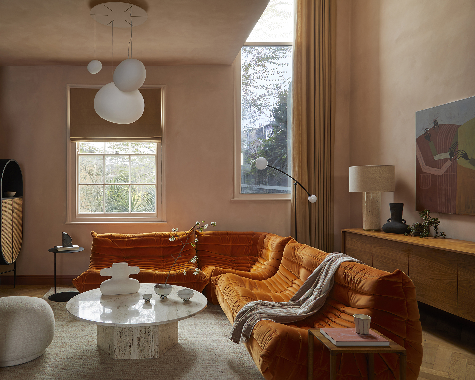 orange togo sofa in a neutral living room with round white coffee table