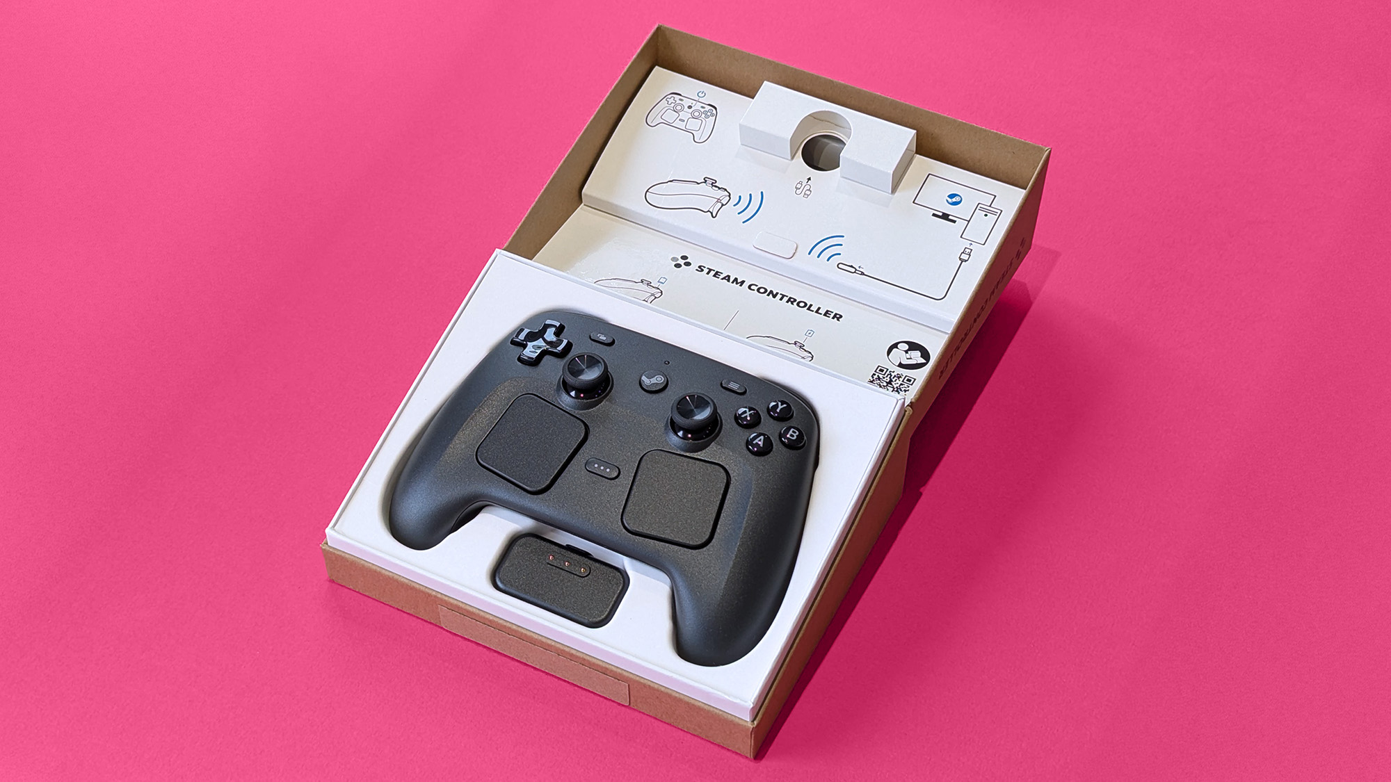 Valve Steam Controller (2026) in its open retail box against a magenta card background