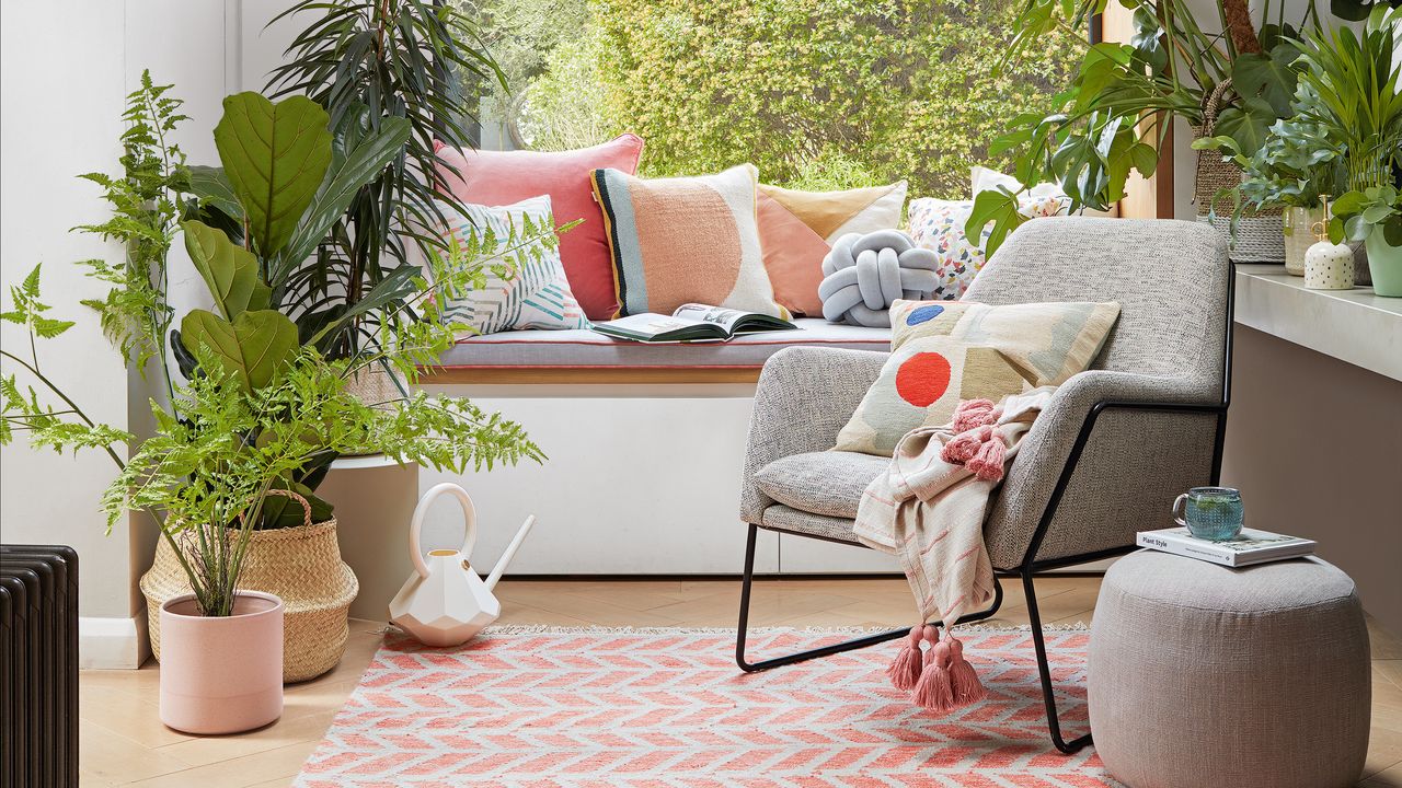 Picture window in a white room surrounded by houseplants on a brightly printed rug