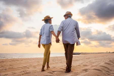 Older couple walking on the beach 