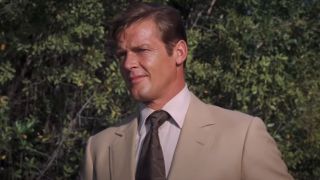 Roger Moore stands in the sun with a questioning look in Live and Let Die.