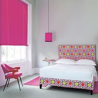 bedroom with bed with cushions chair and pink blinds