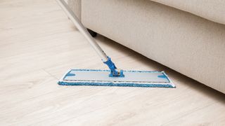 A microfiber mop cleans near a couch