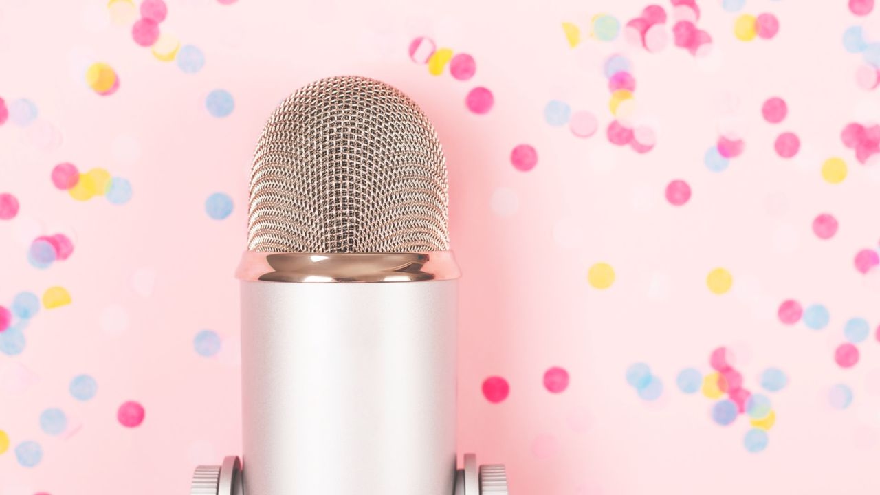 podcast microphone in front of pink background with confetti