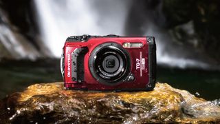 A drenched OM System Tough TG-7 camera on a mossy rock in front of a waterproof