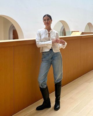 Sasha Mei 6 Elevated Spring Pieces to Buy Now Pretty Tops White Tie-Front Top Jeans Knee High Boots Denim Outfit Idea