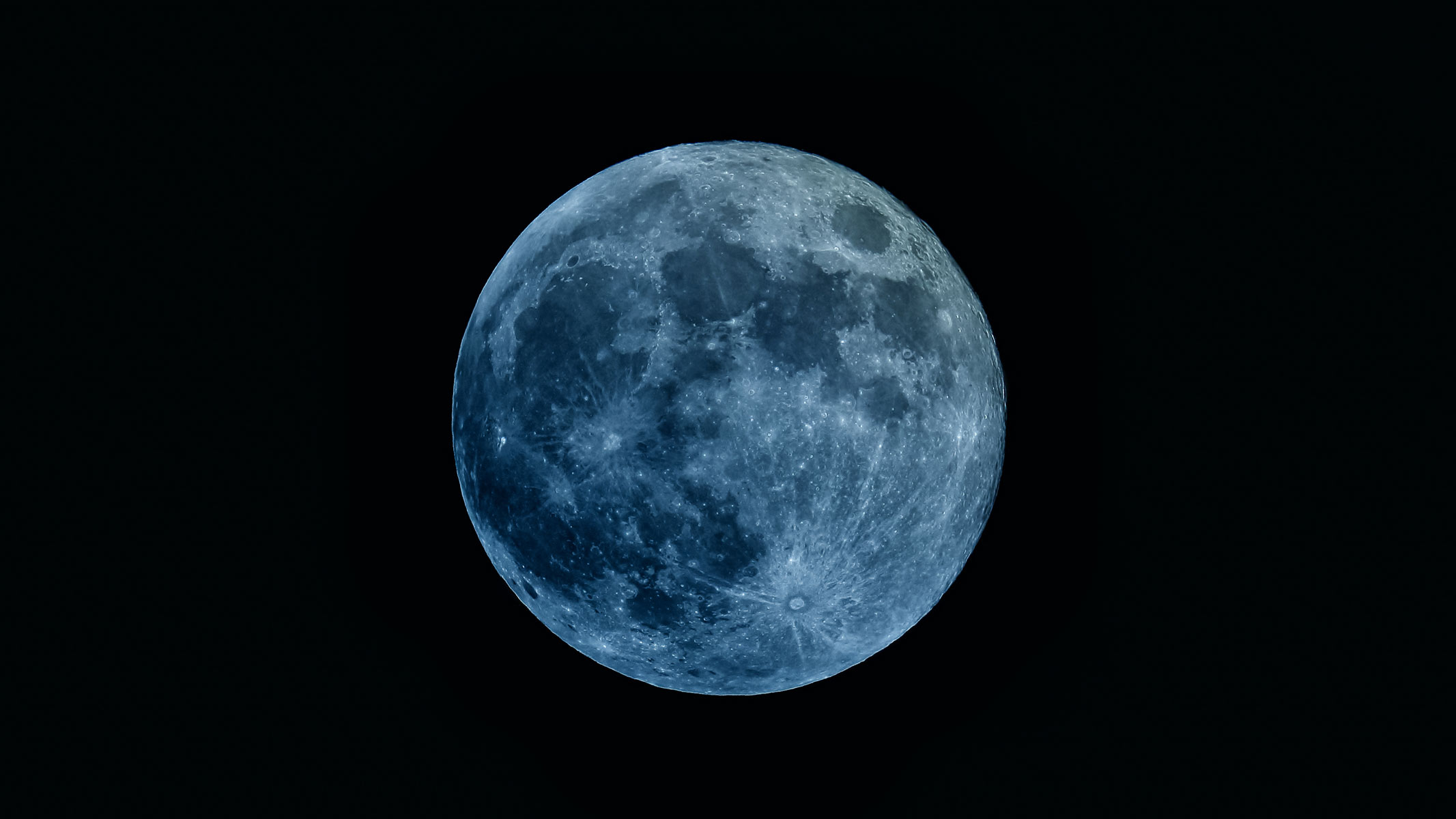 A blue-tinged full moon in a black sky. 