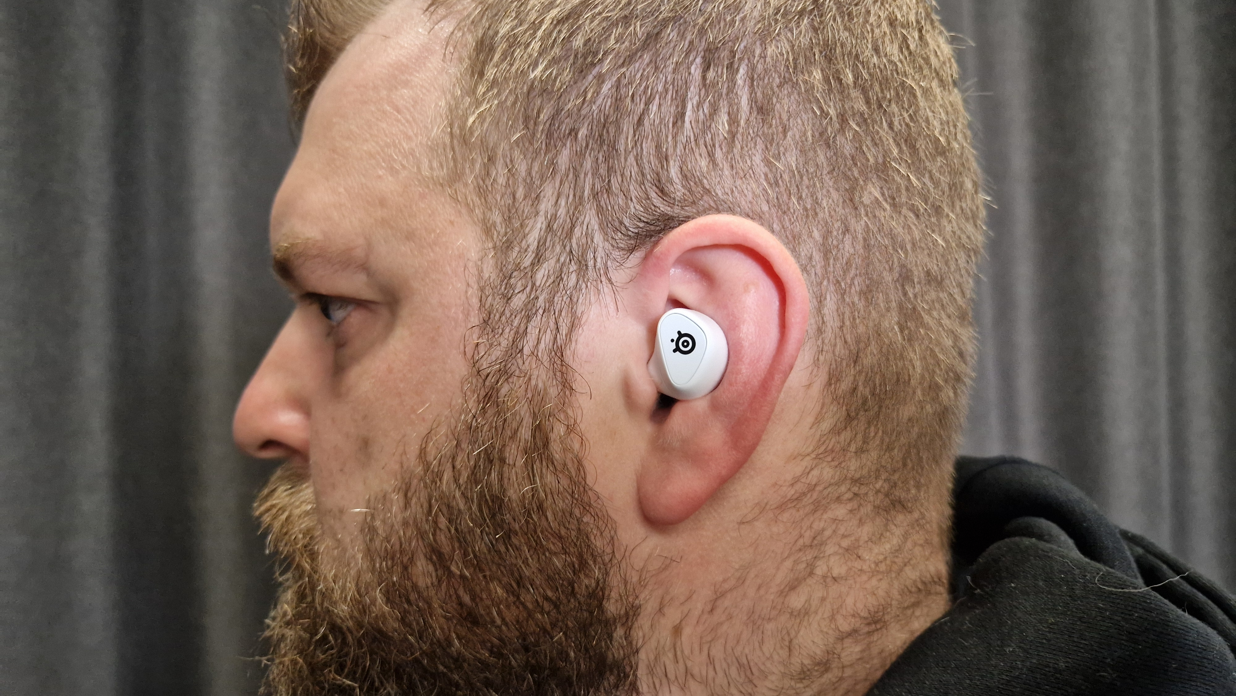 SteelSeries Arctis GameBuds in a man's ear