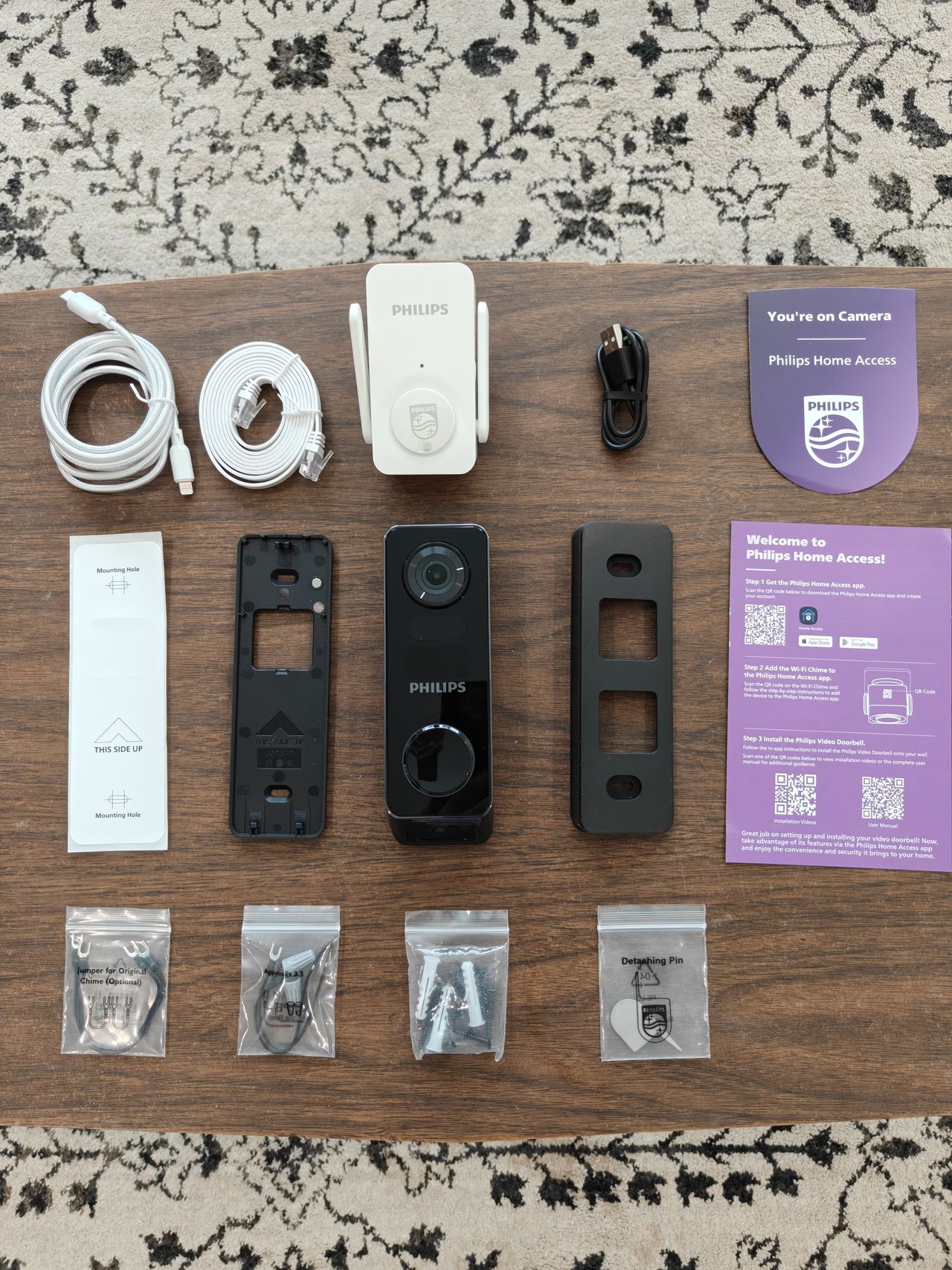 Everything included with the Philips 7000 Series Video Doorbell laid out on wooden table.