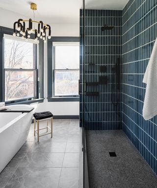 A bathroom with white walls, grey floor tiles and deep blue tiles in the shower