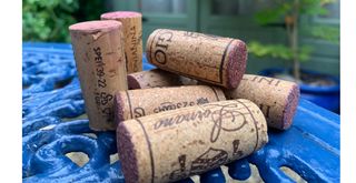 a pile of used wine corks on a blue metal garden table to show how to use wine corks in your garden