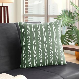 A green and white striped throw pillow on a leather black couch