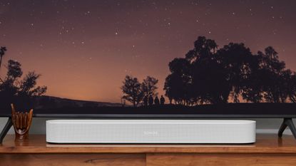 Sonos Beam in white on TV stand below television