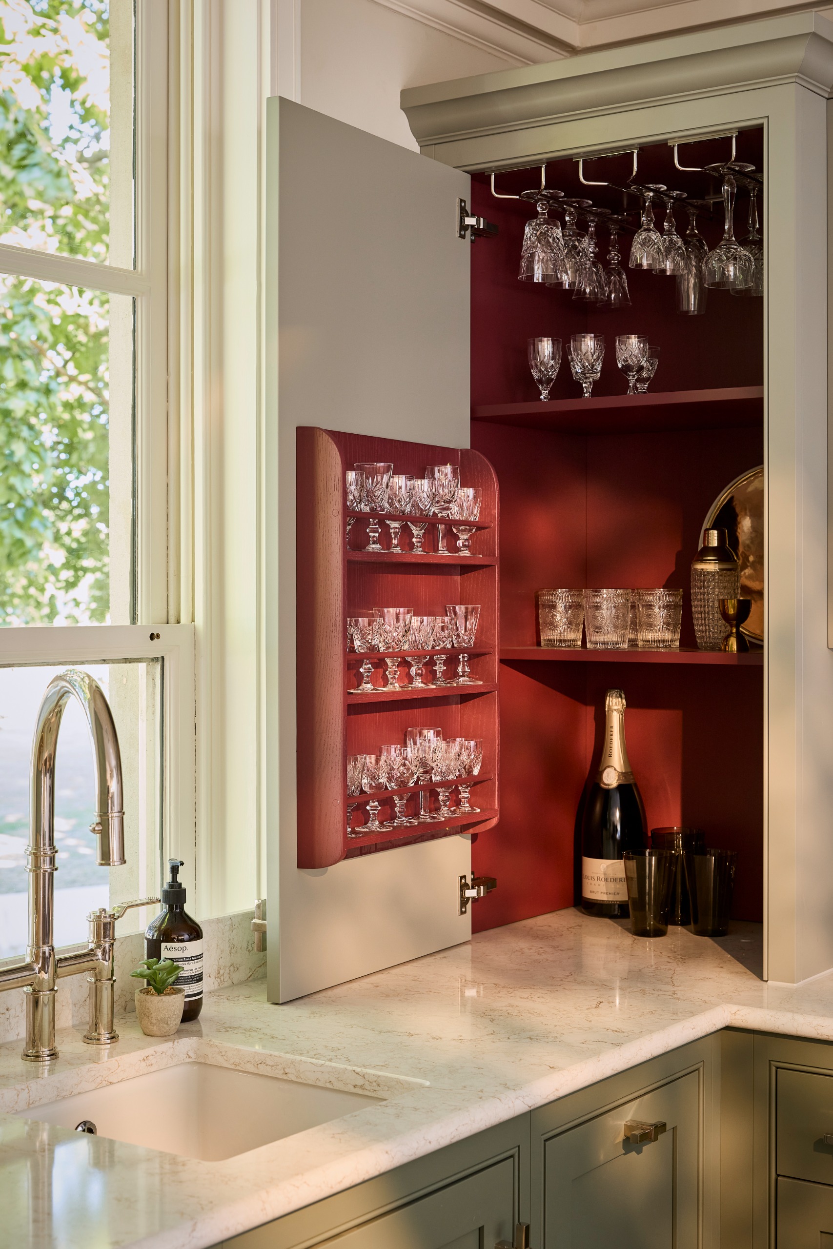 modern shaker kitchen with light sage green cabinets with dark red interiors