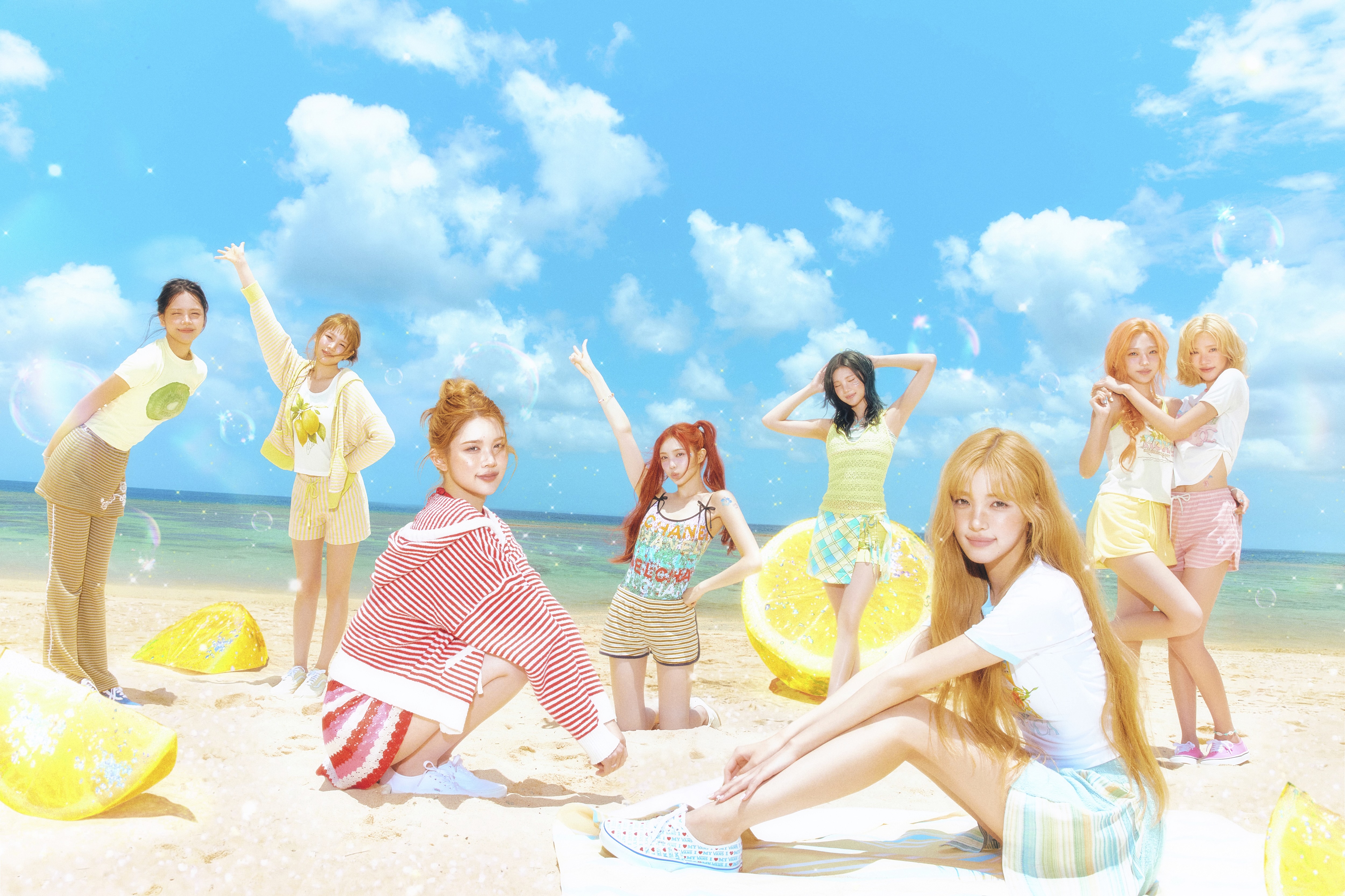 The members of K-pop group Hearts2Hearts (l-r Carmen, Ye-on, A-na, Ian, Juun, Yuha, Stella, and Jiwoo) wear summery outfits while posing on a beach.