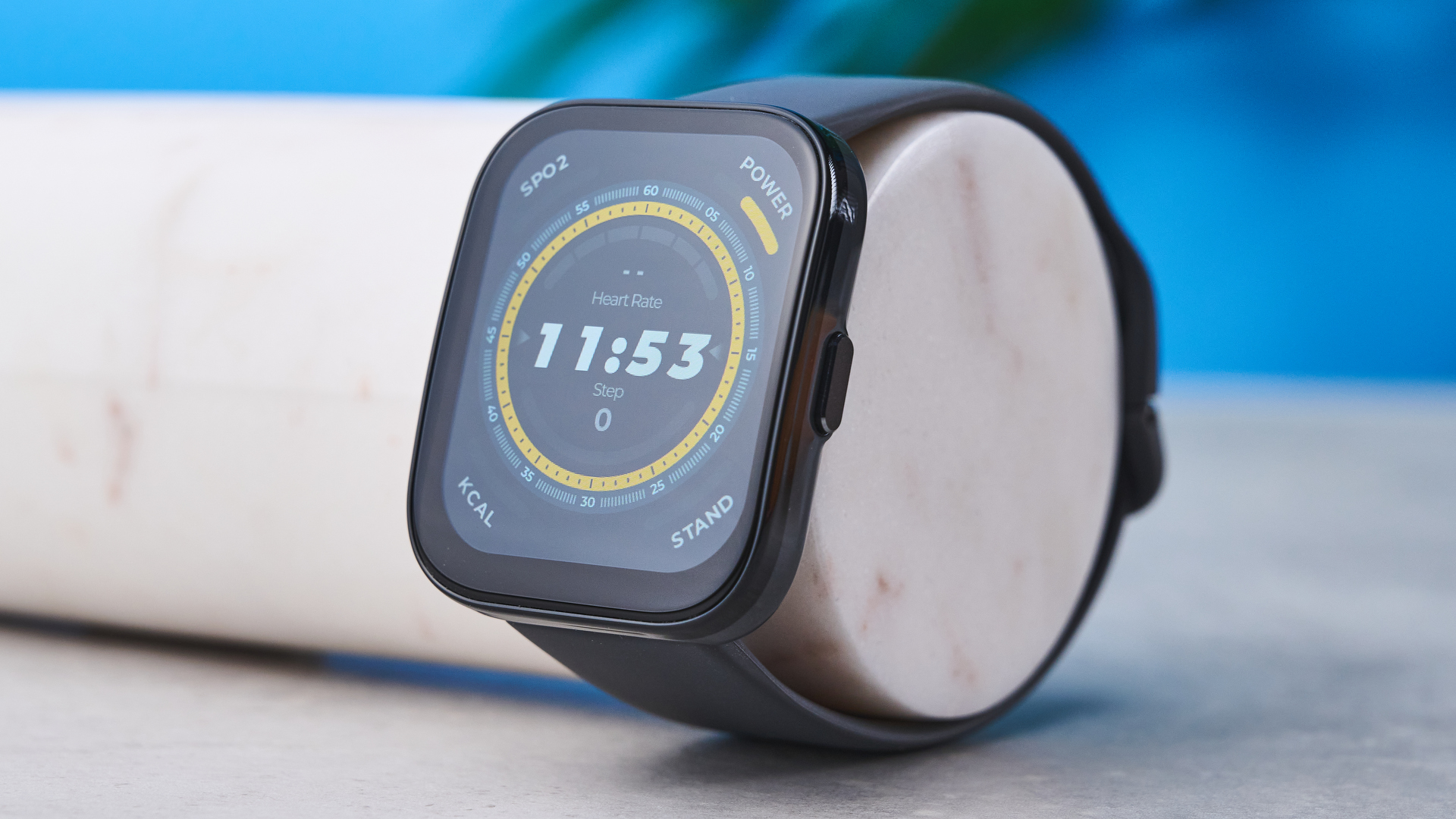 a black fitness tracker Amazfit Bip 5 showing the default yellow and blue toned watch face and fitness capabilities